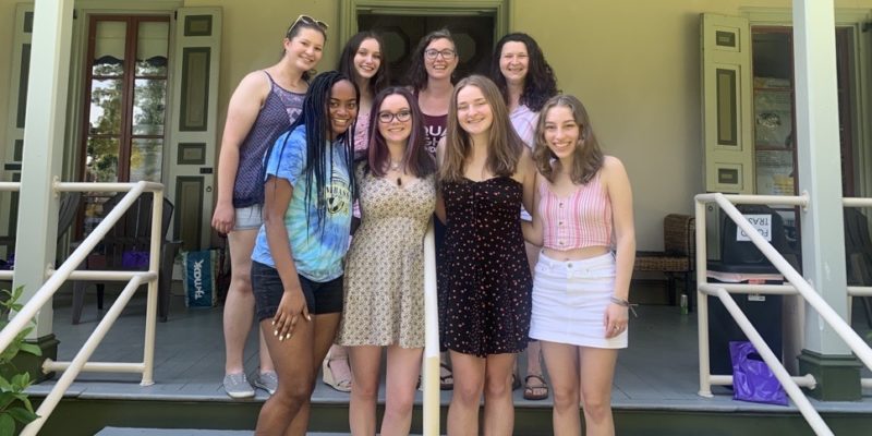 Group of teens and women standing on the steps of historic house