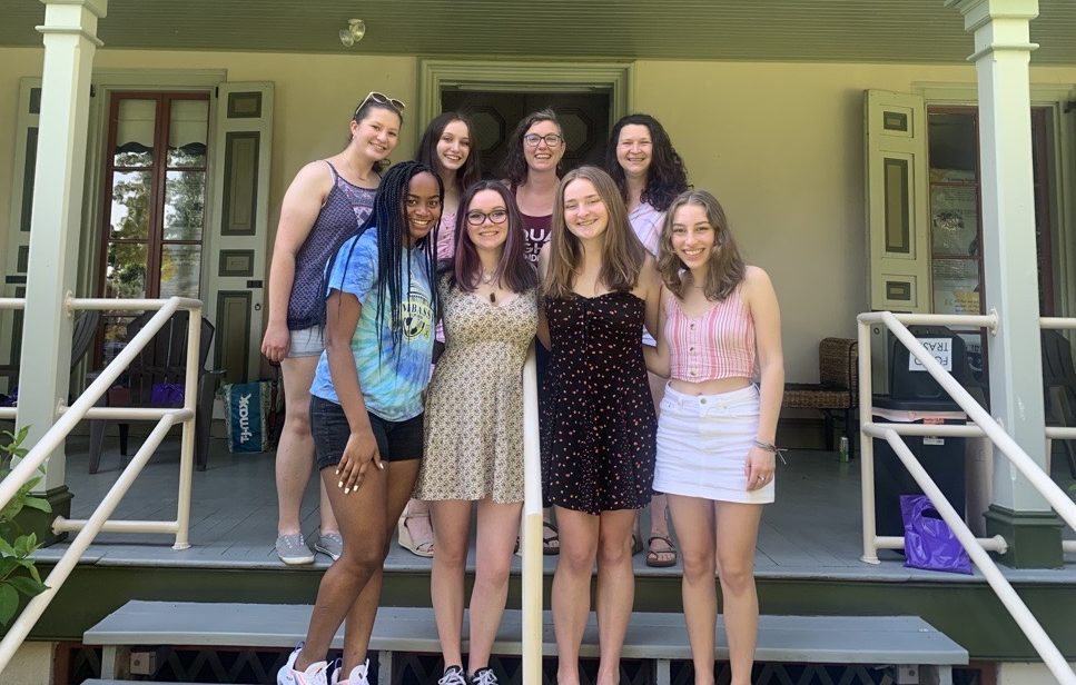 Group of teens and women standing on the steps of historic house